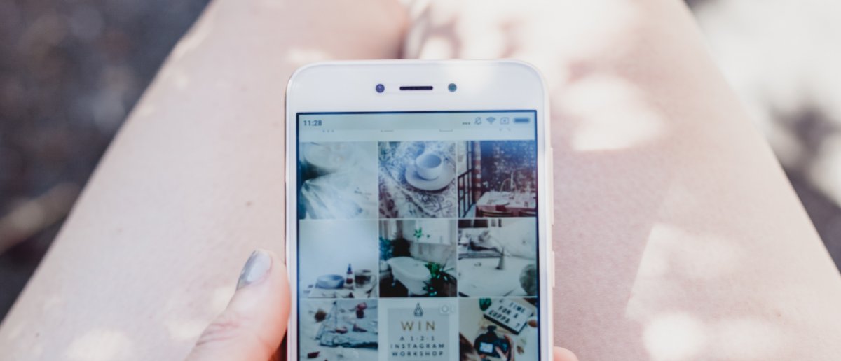 A woman holding a phone, looking at Instagram